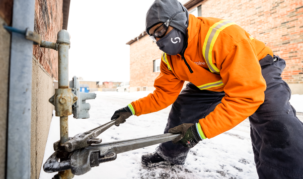 Spire field employee adjusting gas pipe with large wrenches