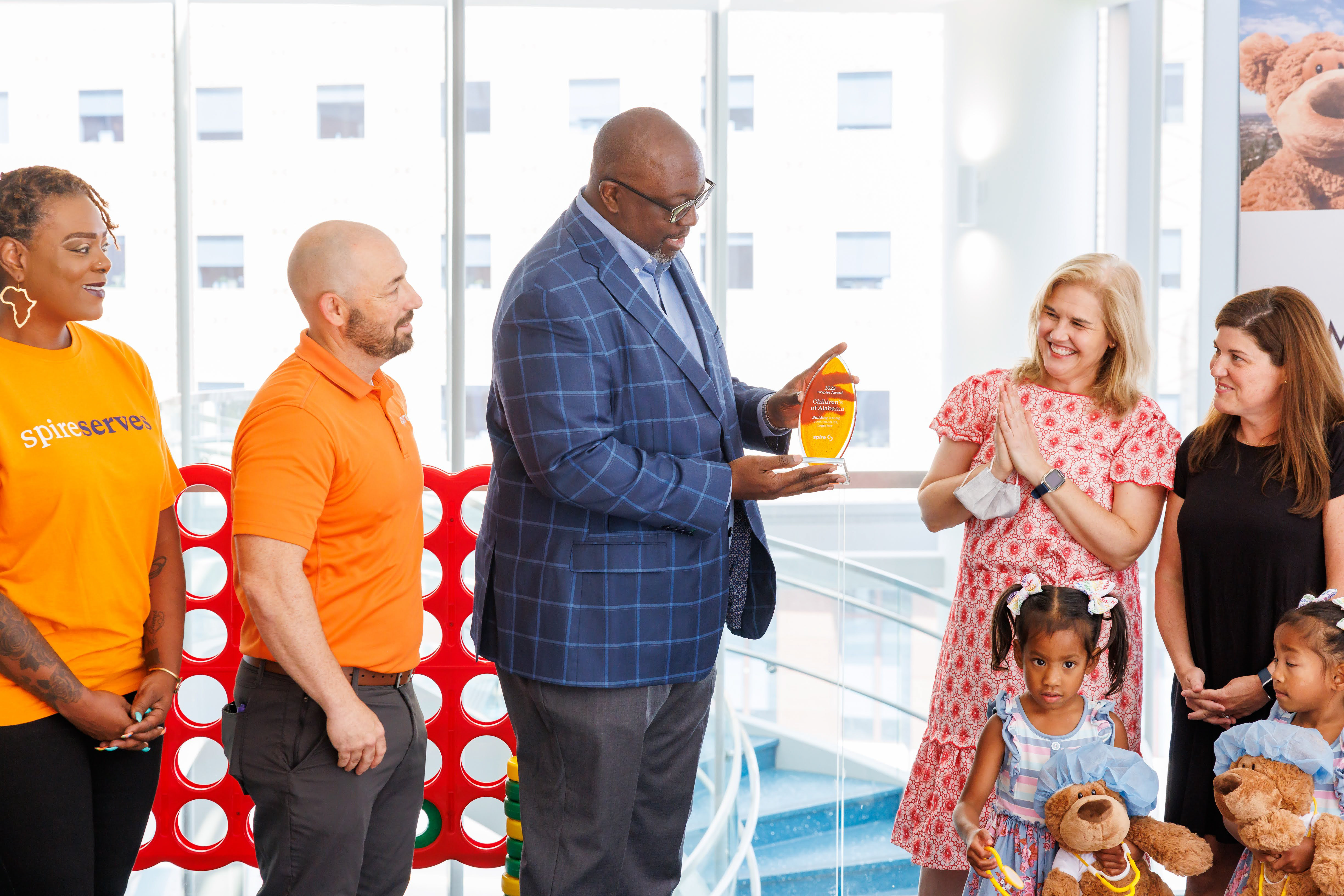 man presenting an award to hospital staff with children and employees present