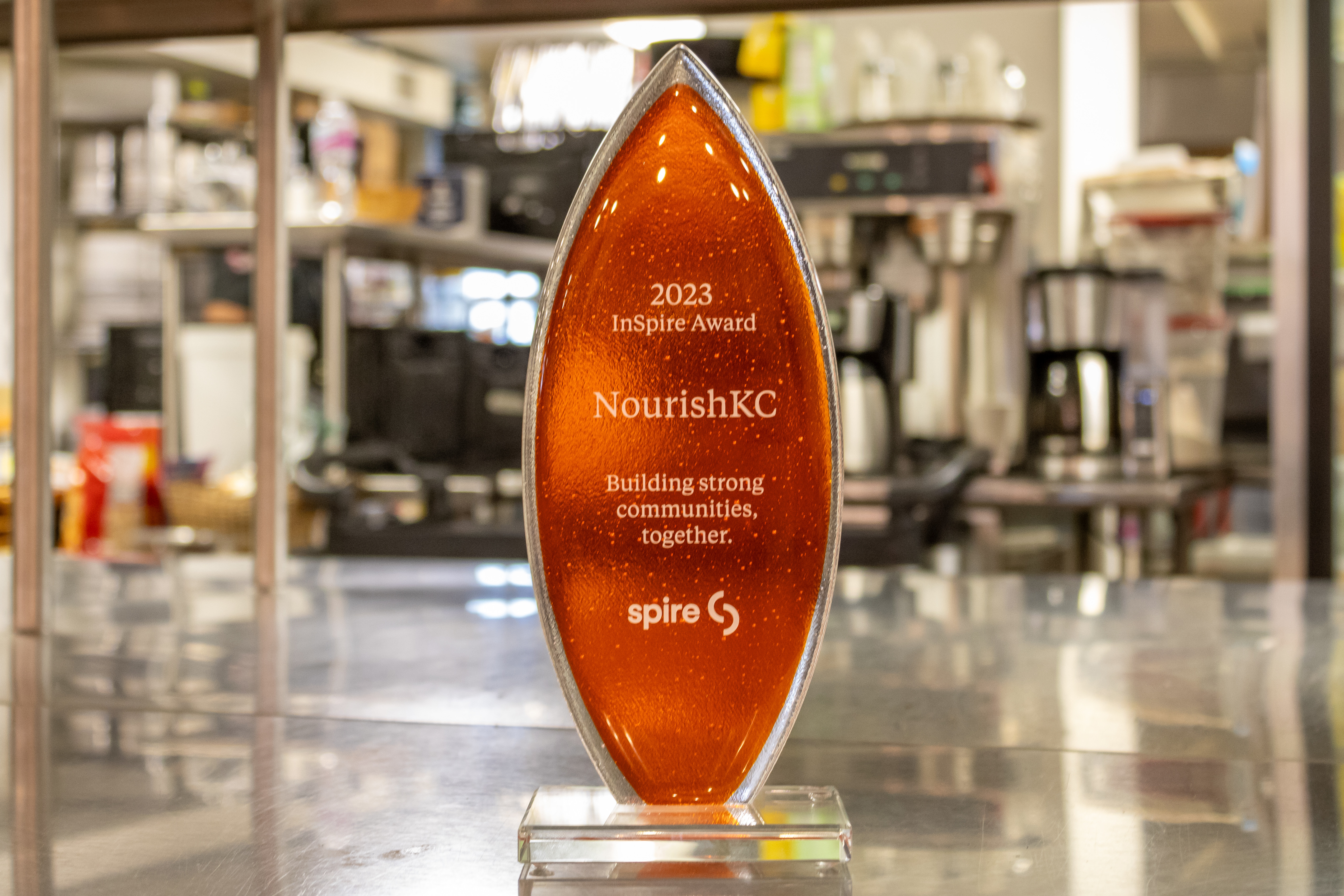 Image of orange trophy. Trophy reads: 2023 InSpire Award Nourish KC Building strong communities together.