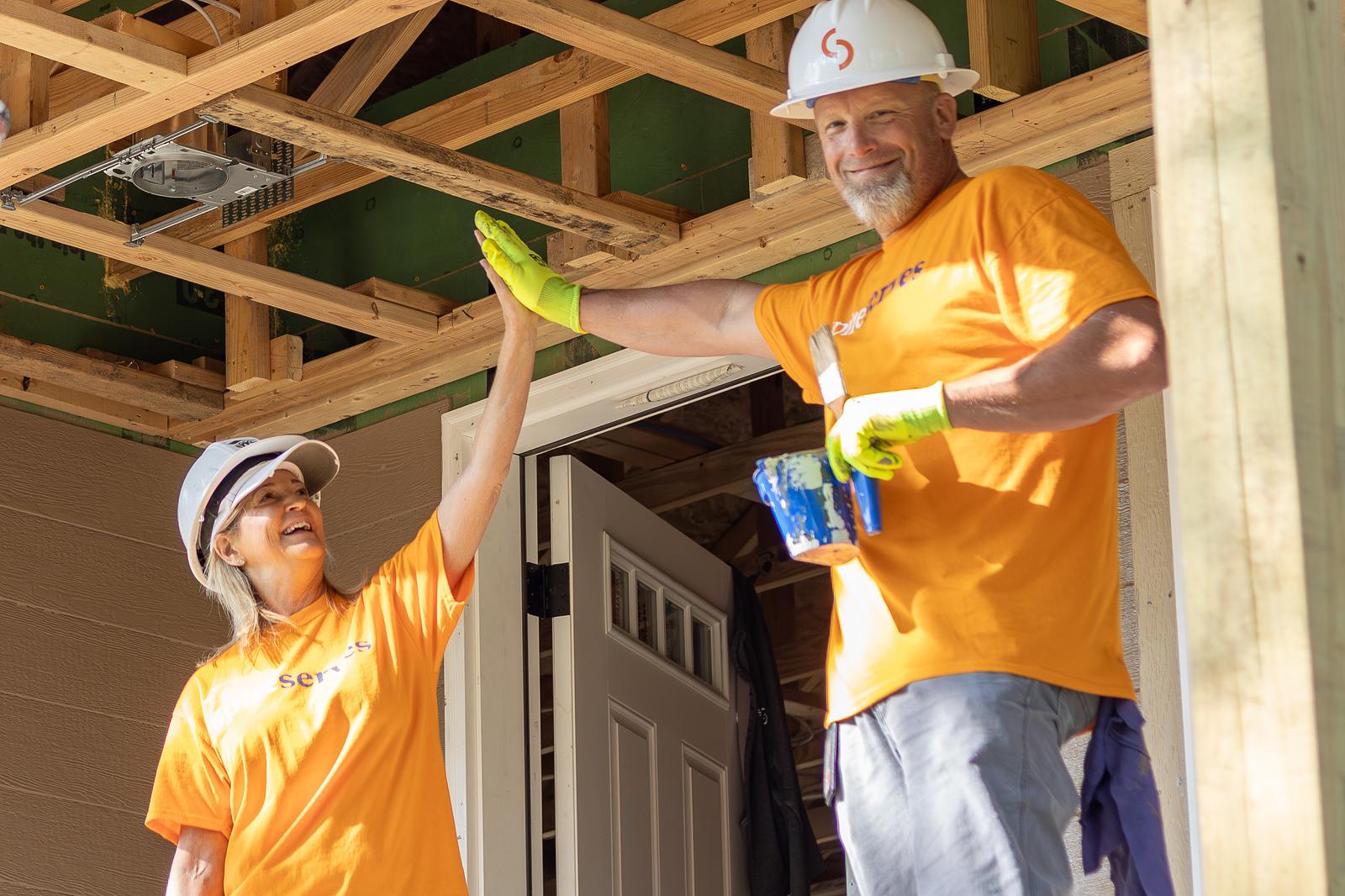 high-fiving while framing a house