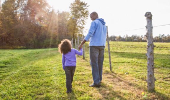 Father and daughter walking through a field