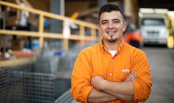 Spire employee with arms folded by truck