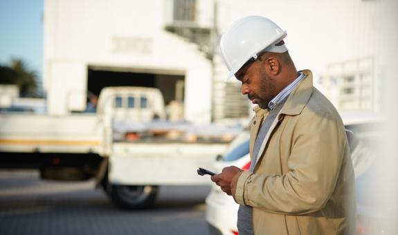 Image of builder wearing hard hat using a smart phone