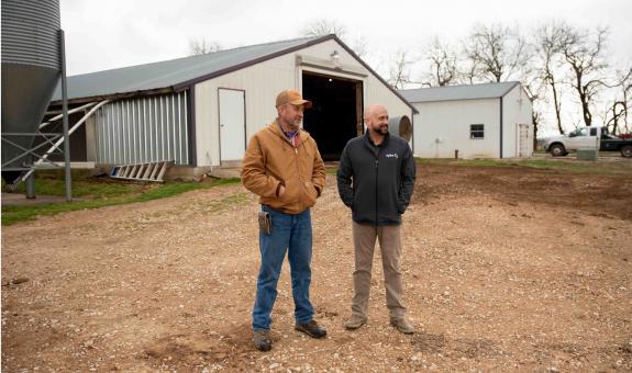 Image of farmer and Spire employee talking by barn