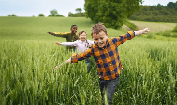Children running through green field