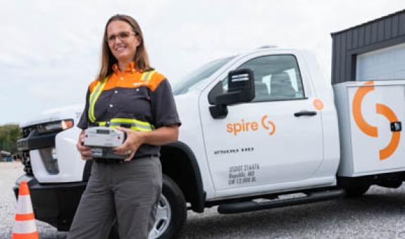 Image of Spire employee holding natural gas meter in front of service truck