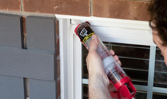 Image of woman caulking her window