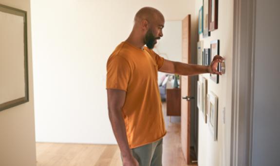 Image of man adjusting thermostat 