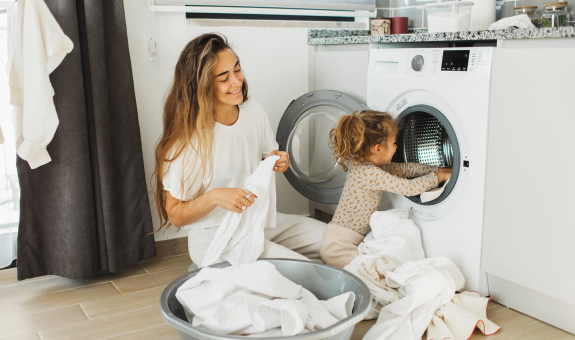 Image of mother and daughter folding clothes out of the dryer