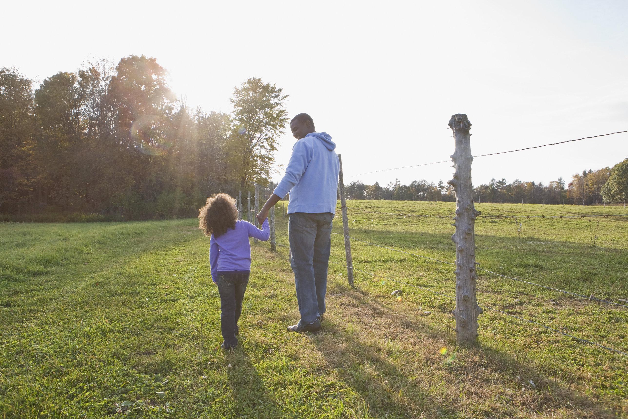 Father and daughter walking through field