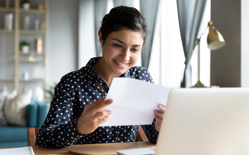 Image of woman looking at paper application in front of computer