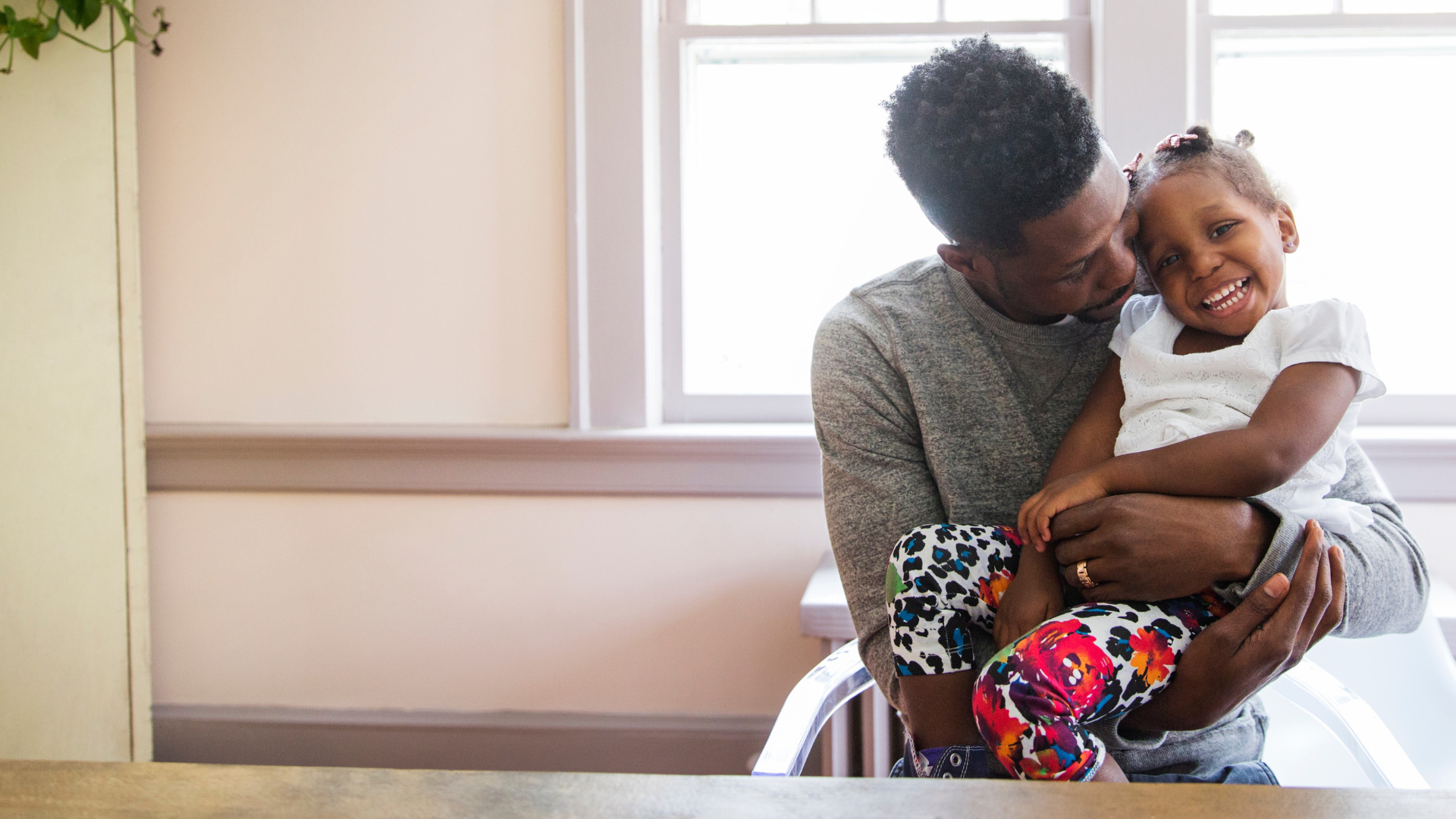 Image of African American father and daughter smiling indoors