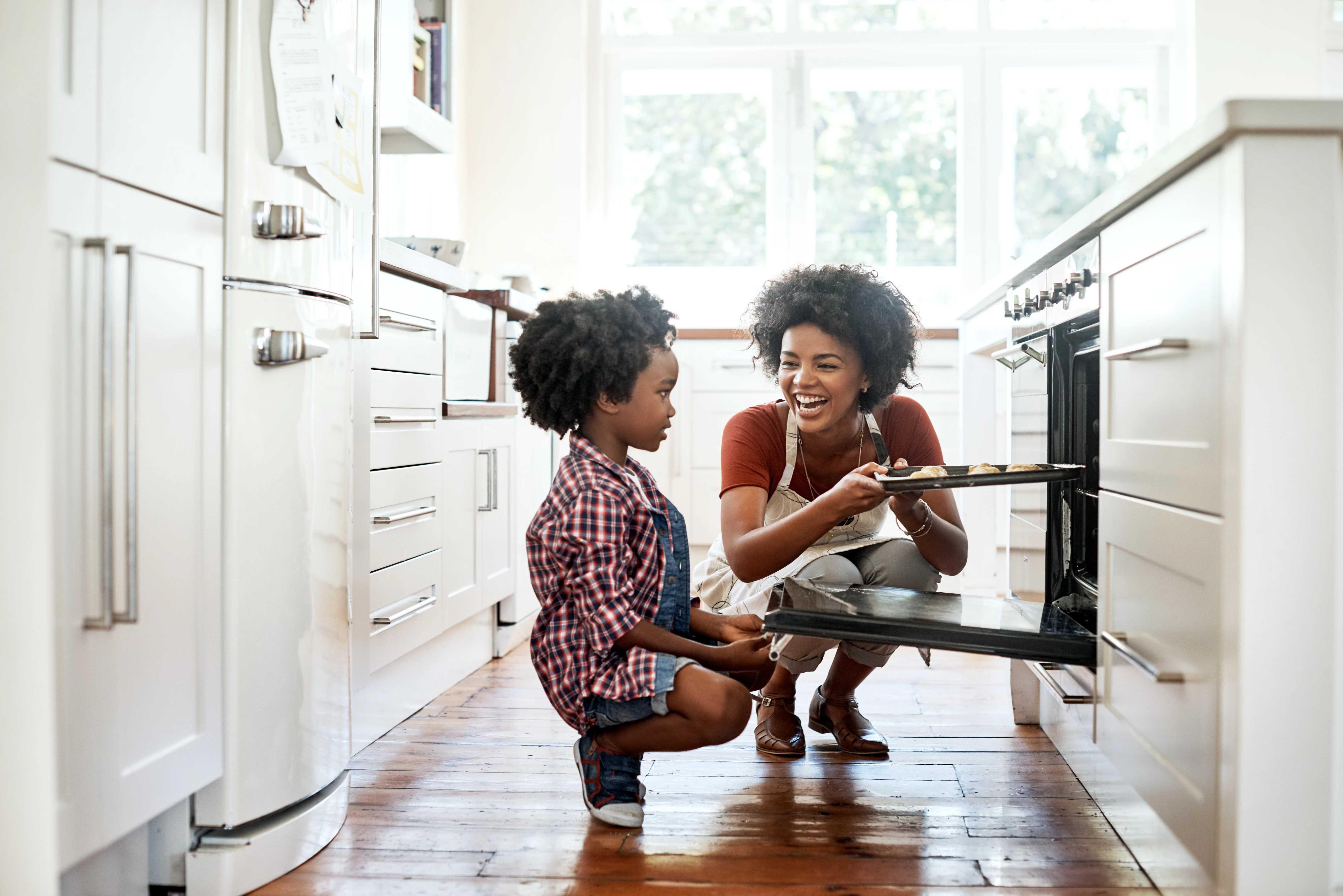 Image of woman and child putting muffins into the oven