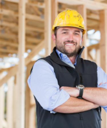 Image of contractor standing in front of wood at homebuilding