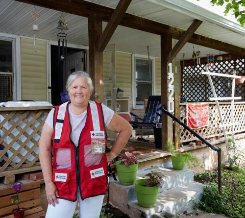 Image of: Red Cross volunteer standing in front of her home