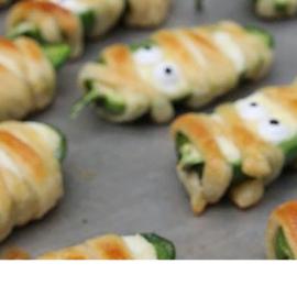 Jalapeno poppers on a baking sheet decorated as mummies
