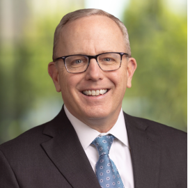 Image of Spire COO Scott Doyle. He is wearing a black suit with a blue tie.